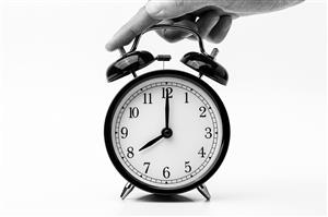 person touching an old-fashioned two bell alarm clock